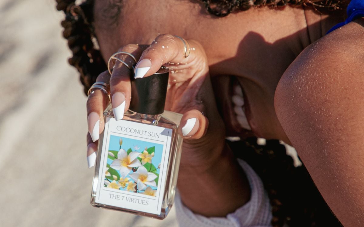 best solar fragrances: A woman holding a bottle of The 7 Virtues Coconut Sun Eau de Parfum