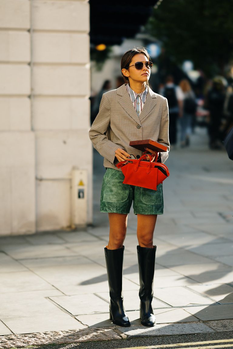 A woman wears green shorts with black wide-shafted knee high boots
