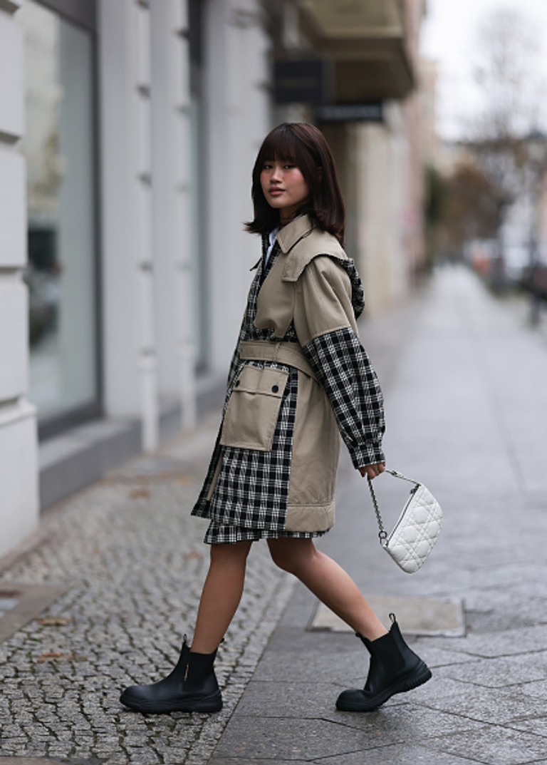 A woman wears a long coat with black Chelsea boots