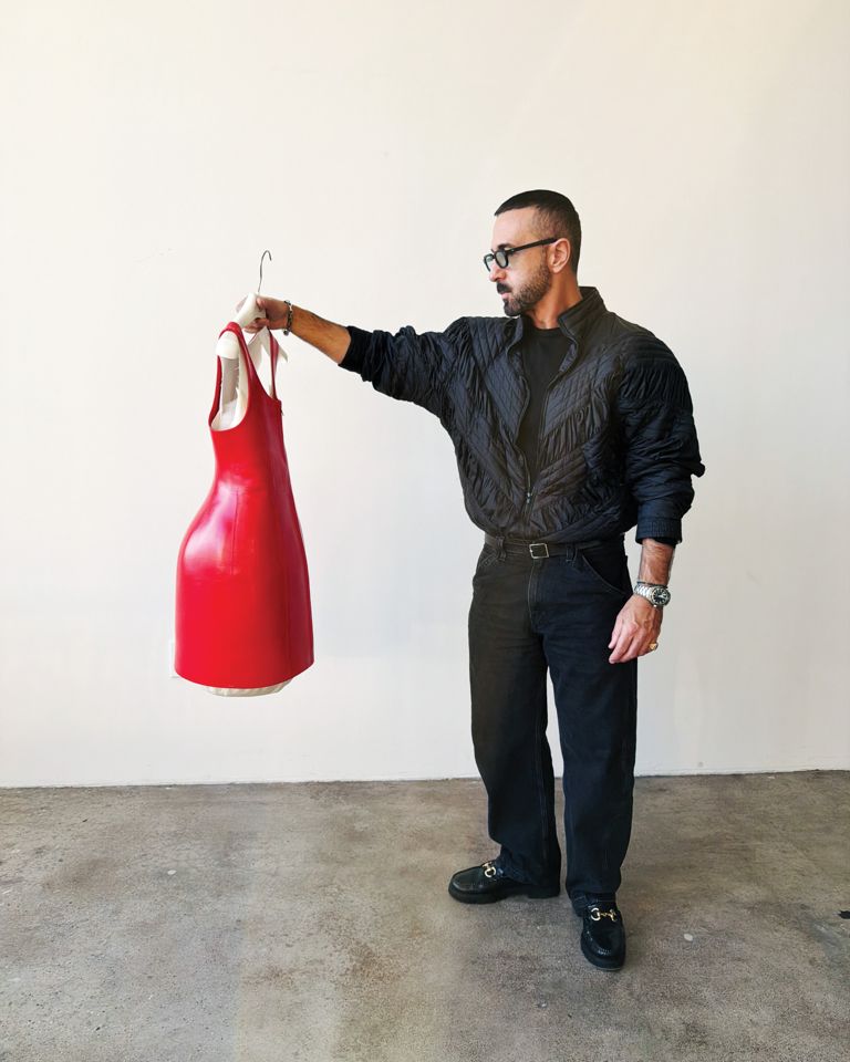 FASHION’s Senior Creative Director George Antonopoulos holds up a red Loewe dress on set during FASHION's April 2026 cover photoshoot with Zazie Beetz.