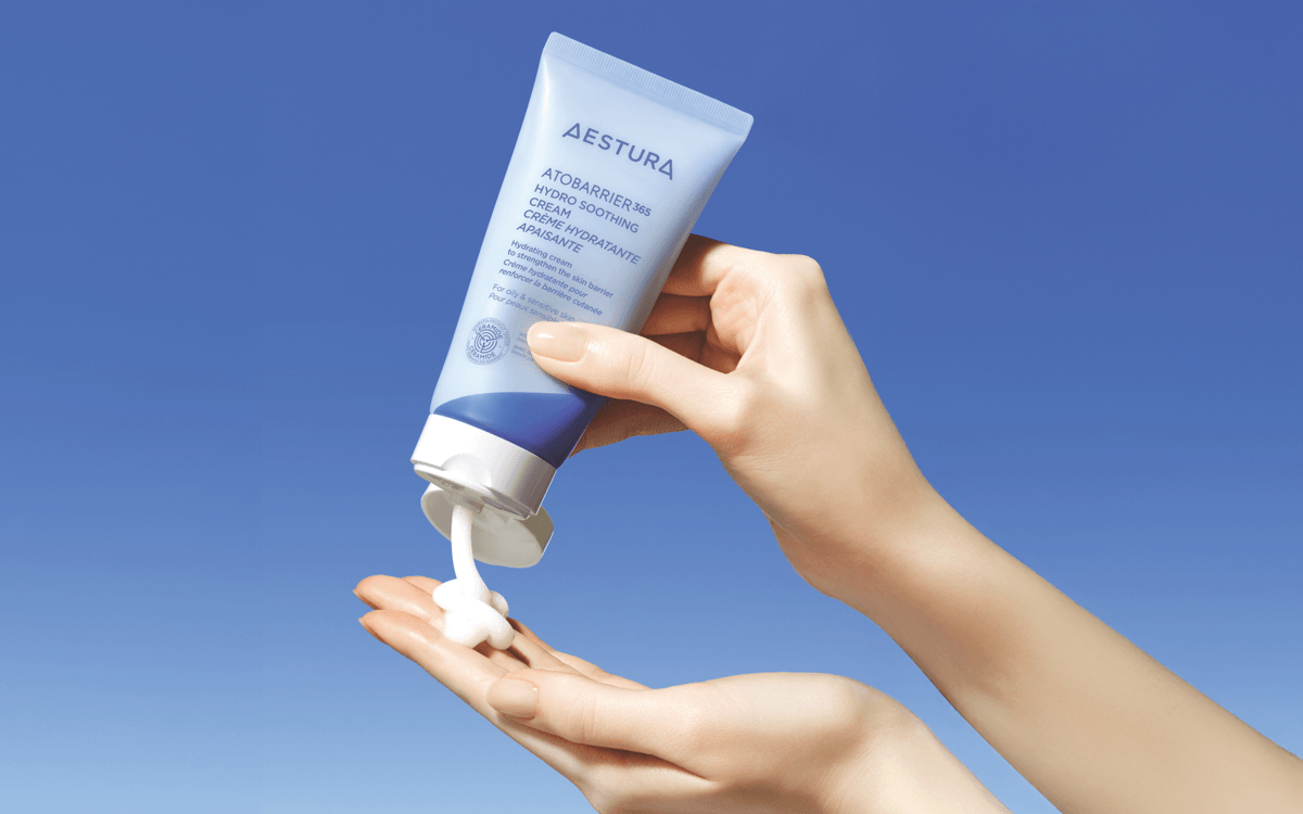 Close-up of a woman's hand squeezing out the AESTURA hydro soothing cream.