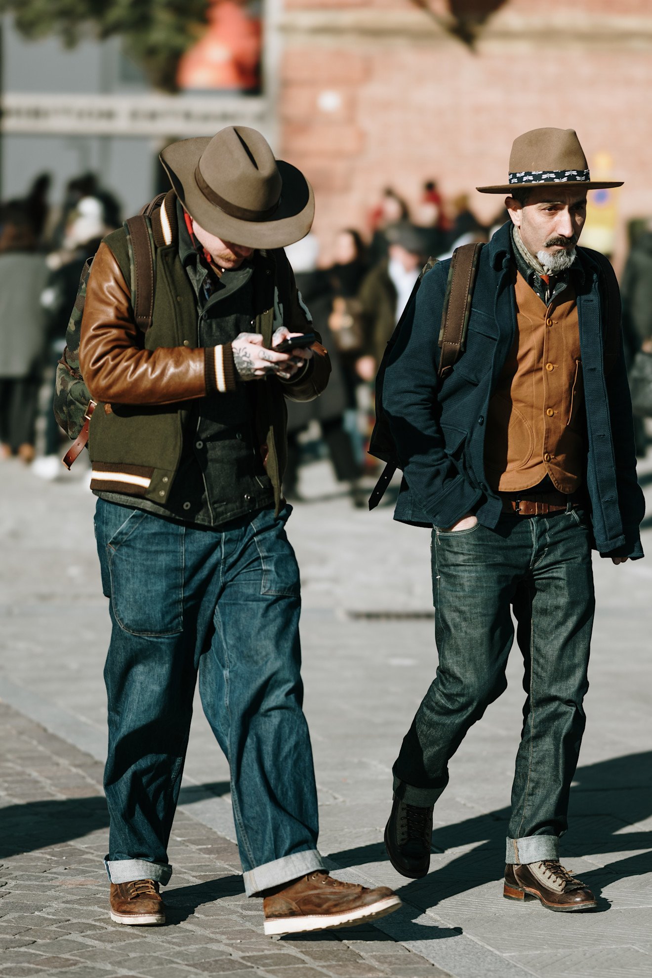 While both men wear hats, jackets, and jeans, their distinct styling choices illustrate how to find your style, suggesting that even with common trends, individual expression is key. This addresses the question of why are we dressing the same.