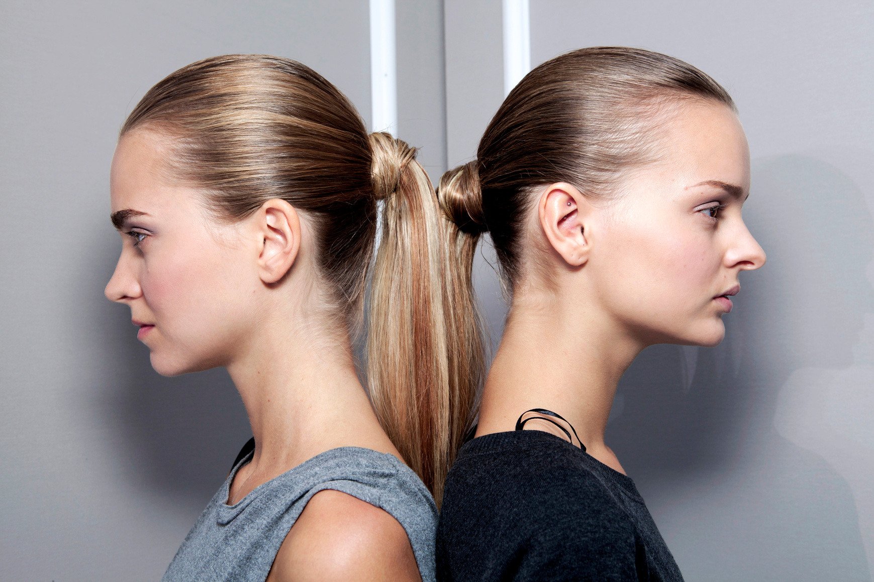 slick back hair: Two models with slick back ponytail hairstyles facing opposite directions